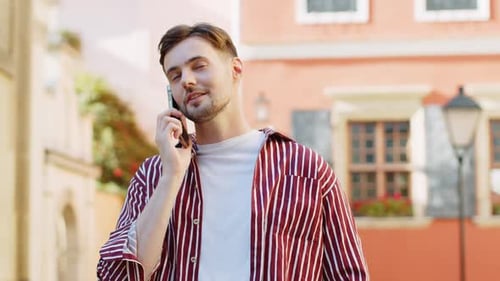 Happy Handsome Man Having Remote Conversation Talking on Smartphone Good News Gossip in City Street