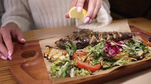 Squeezing Lemon on Grilled Fish with Salad