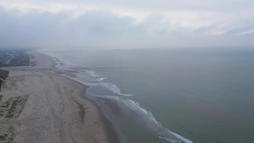 A serene aerial view of a vast coastline with gentle waves washing onto the sandy beach