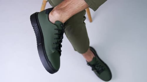 Man wearing dark green shoes with black laces and soles.