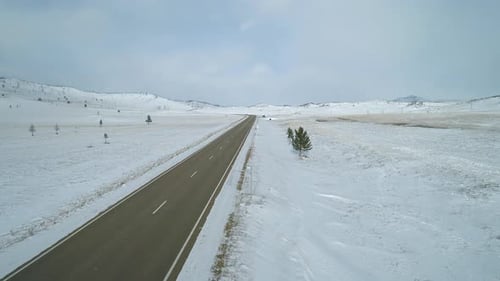 Luftlandschaft, Intercity-Straße in ländlicher Gegend, umgeben von verschneiten Feldern und Hügeln
