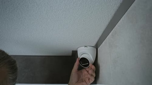 Man Adjusting Home Security Camera with Tablet