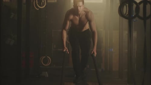 Muscular Man Does Battle Rope Exercise in Gym