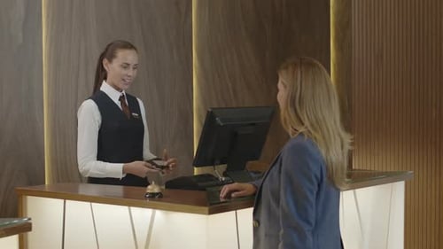 Hotel Receptionist Giving Passport to Woman after Check-In