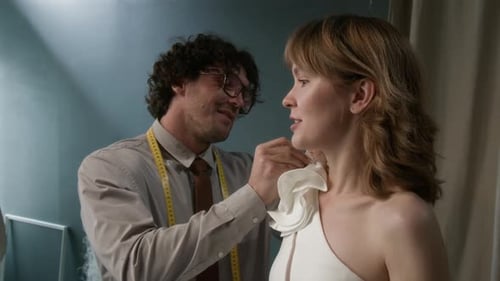 Costureira fixando elemento decorativo no vestido de noiva enquanto trabalha com a noiva