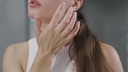 Close Up of Pretty Beautiful Young Woman in Front of Bathroom Mirror Applies Cosmetic Procedure on