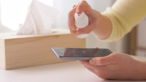 Woman Cleaning Cell Phone Screen with Sanitizer