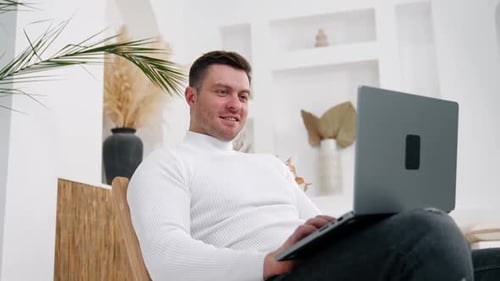 Man Working on Laptop Computer in Modern Home