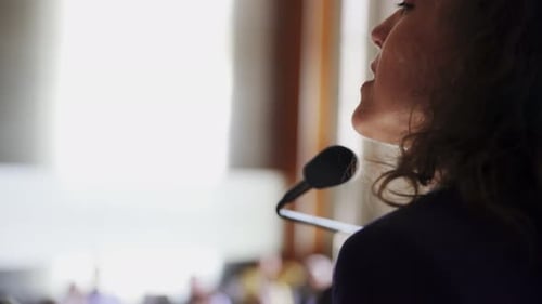 Woman Speaker at Corporate Conference Using Microphone