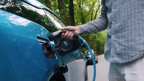 Man plugging an electric car or EV at charging station at green. Save ecology alternative energy sus