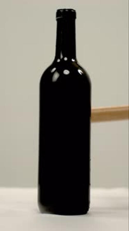 Bottle of Red Wine Smashed with a Stick in Vertical