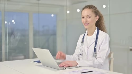 Doctor Giving Thumbs Up While Working on Laptop