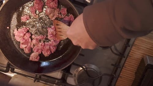 Cooking Meat Chunks with Spatula on Gas Stove