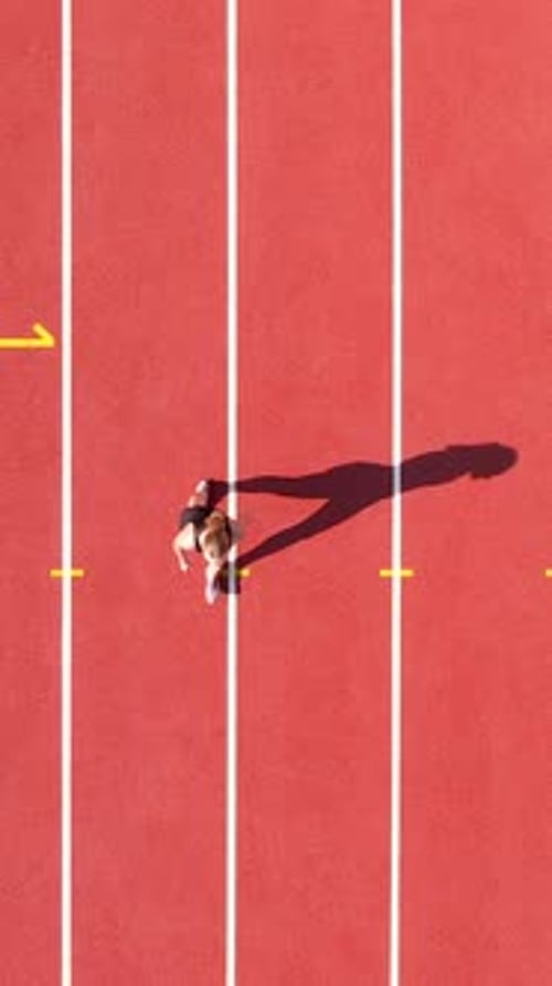 Aerial Top Down View Of Female Athlete Running On Red Track