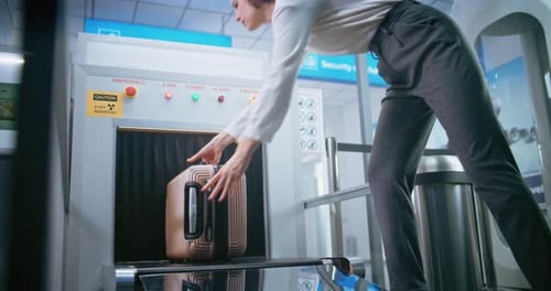 Airport Security Checkpoint Passenger Places Suitcase on Xray Conveyor Belt for Baggage Screening