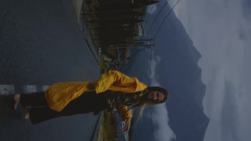 Beautiful Girl in a Yellow Raincoat is Running Along the Road A Woman Enjoys the Rain Autumn Day