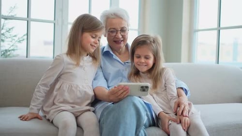 Grandmother with Granddaughters Using a Cell Phone on Couch