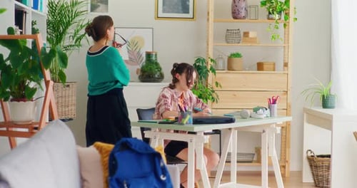 Girl Studying at Desk with Woman Watching