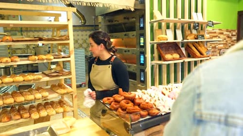 Man Buying in an Artisan Bakery Attended By Friendly Saleswoman