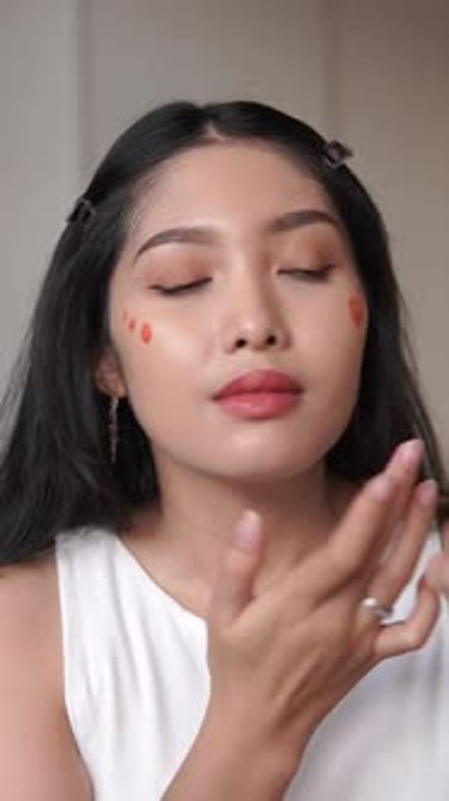 Pretty young Asian woman applying blush on cream. Beauty tips, beauty vlogger concept.