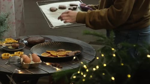 Die Frau, die Weihnachtsessen kocht, legt gebackene Weihnachtslebkuchen auf den Teller