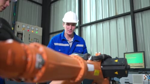 Engineer and technician working with robot arm in factory. Industry and engineering concept.