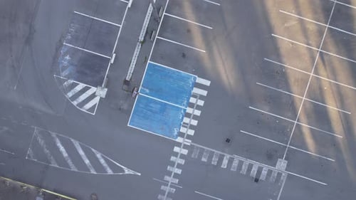 Washed out lines of empty asphalt parking lot, aerial top down spinning shot