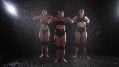 Three Sexy Women Begin a Synchronized Dance Under the Spray of Water in a Dark Studio