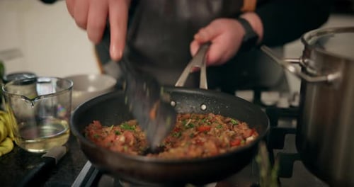 Person Cooking Meat and Vegetables in Skillet