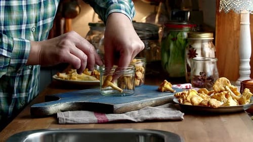 Filling Jars with Fresh Chanterelle Mushrooms in Kitchen