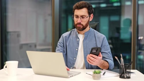 Businessman Working with Laptop and Smartphone in Modern Office