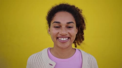 Smiling Woman with Curly Hair Against Yellow Background