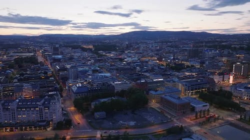 Backwards Fly Above Buildings in Urban Borough Cityscape Against Color Twilight Sky Revealing Water