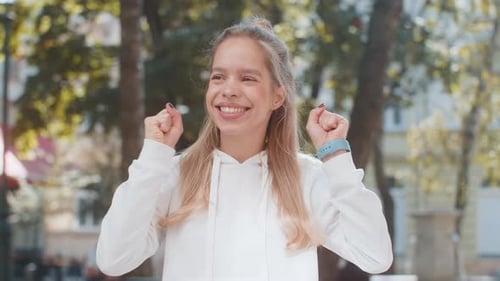 Young Woman Looking Surprised Clenching Fists Shocked By Sudden Victory Standing on City Street