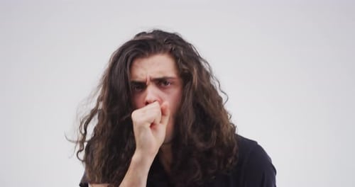 A handsome young man coughing against a grey background