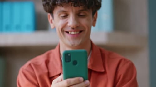 Man Smiling While Looking at a Cellphone