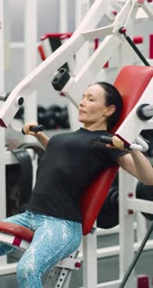 Woman Using Chest Press Machine in Gym