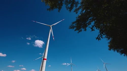 Wind turbines rotating slowly in the wind in beautiful blue sky. Energy production. Low angle view.