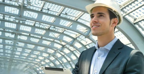 A young handsome, engineer, foreman, architect (builder) working with a tablet, at the station, we