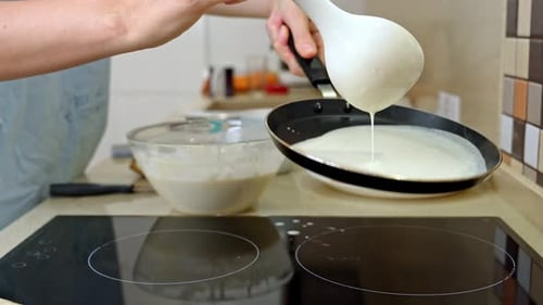 Frau kocht Pfannkuchen auf einem modernen Küchenherd