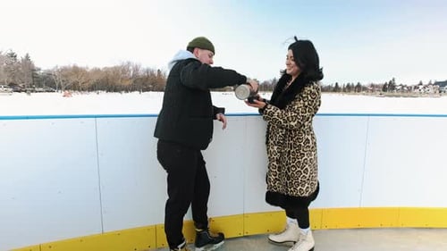 Friends Ice Skating in Winter Sharing a Beverage