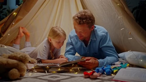 Father Reading Bedtime Story to Little Girl in Tent