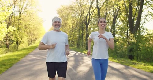 Healthy Senior Man and Young Woman Jogging Together