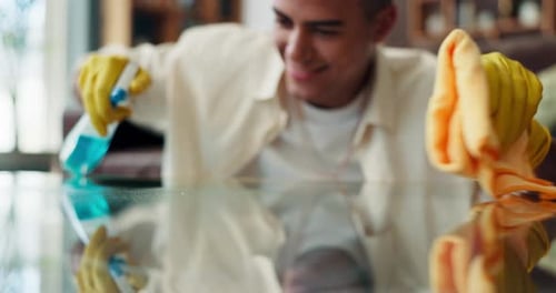 Young Man Cleaning Glass Table at Home