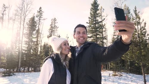 Cheerful caucasian couple takes a snowy selfie in a canadian winter forest