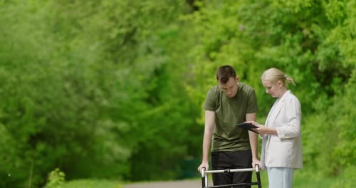 Young Man Walks with Walker and Therapist Outdoors