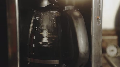 Black Coffee Dripping Inside Glass Pot Of Coffee Maker In The Morning. close up