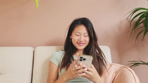 Smiling Woman Using Smartphone on Cream Couch