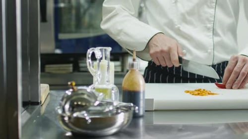 Professional chef in a commercial kitchen in a restaurant or hotel is slicing green vegetables.