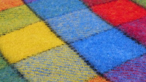Close-up view on the bright textured multicolored wool fabric in a large check rotated